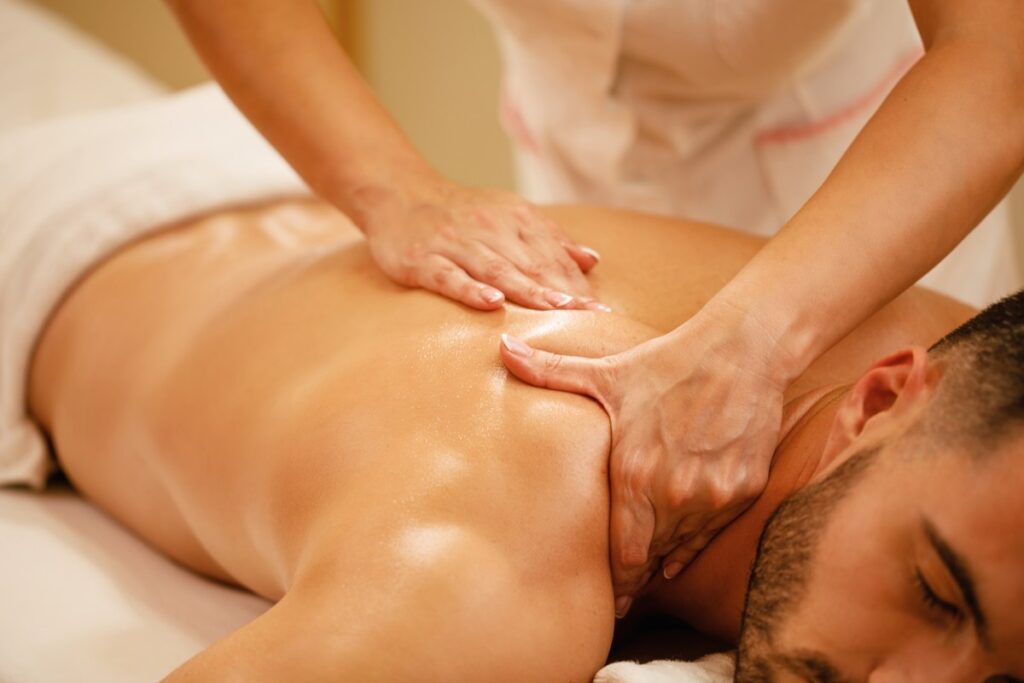 A professional massage therapist at MOssage Therapeia gently massaging a client's scalp and upper back, focusing on releasing head and shoulder tension in a calming Beverly Hills studio.